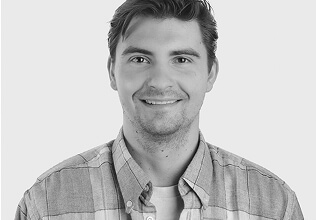 Portrait of person with short hair wearing plaid button‑up shirt against plain light background, well‑lit and suitable for identification or professional use.